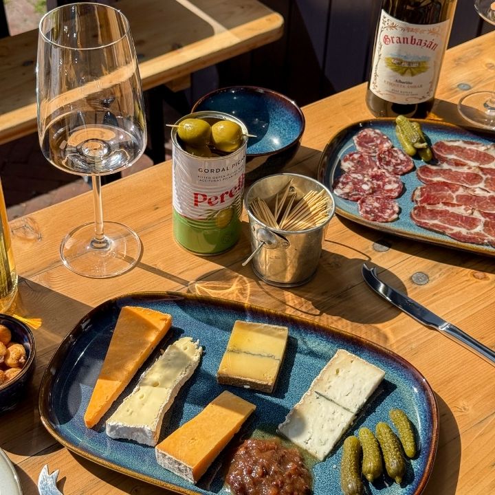 Table with a platter of cheese, charcuterie, and a glass of wine.
