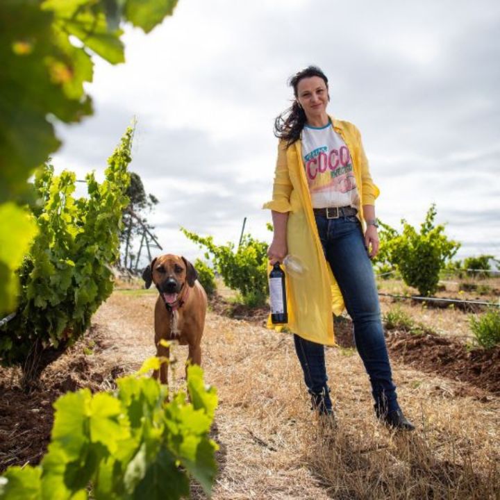 Dandelion Vineyards Winemaker Elena Brooks in a yellow coat with a dog in a vineyard