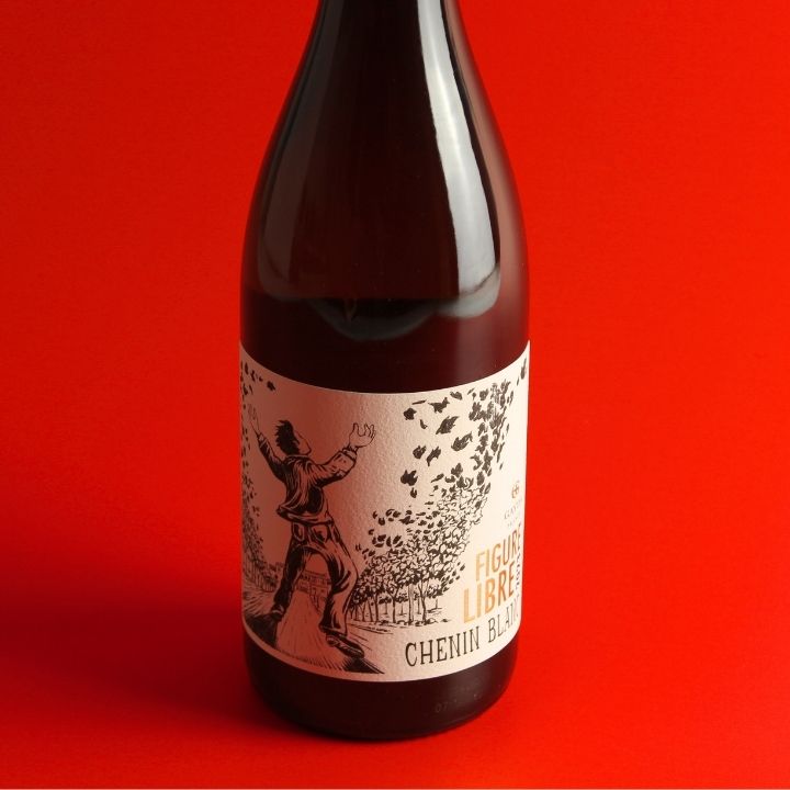 A dark brown glass wine bottle with a cream-colored label featuring a black illustration of a figure throwing leaves, with the text 'FIGURE LIBRE' and 'CHENIN BLANC'. The bottle is set against a solid red background.