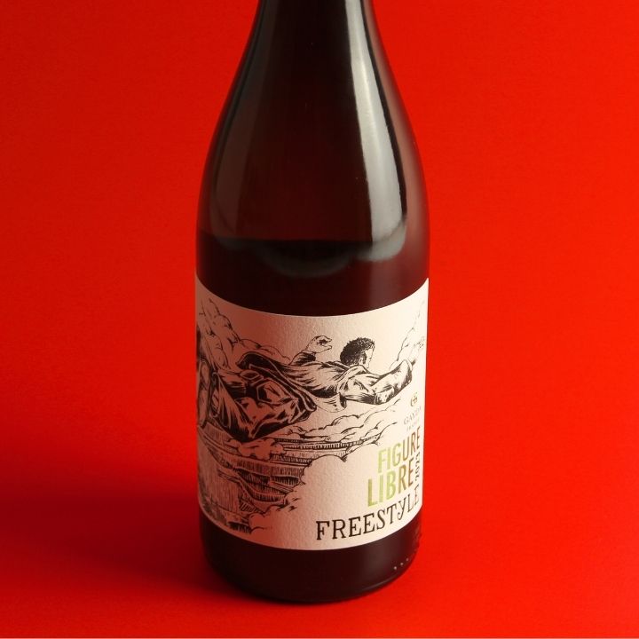 A dark glass bottle with a cream-colored label featuring a black illustration and the text 'FIGURE LIBRE FREESTYLE', set against a solid red background.