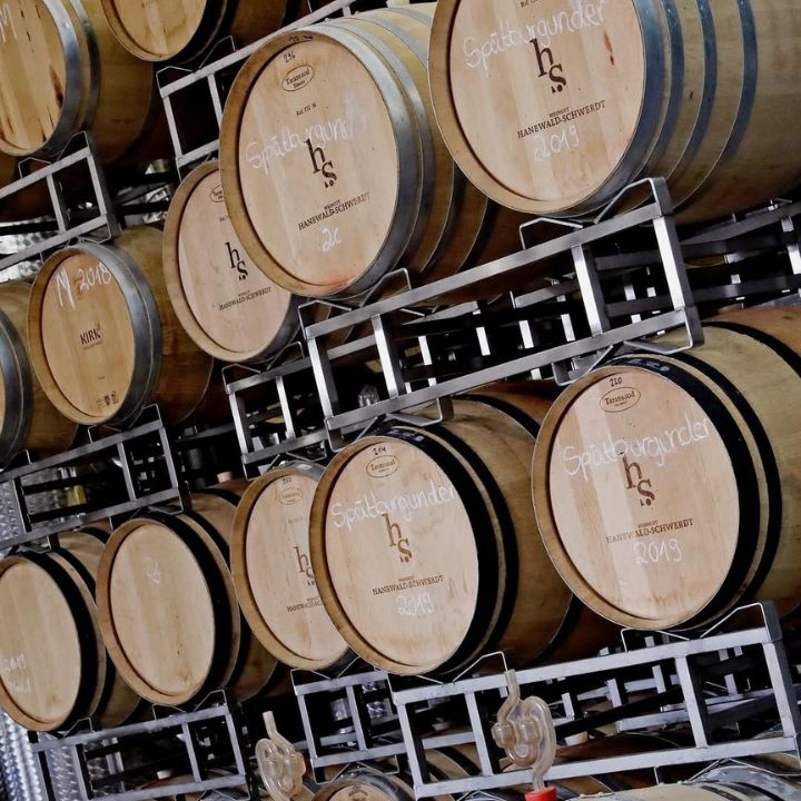 Wooden barrels with Hanewald Schwerdt logo on a metal rack