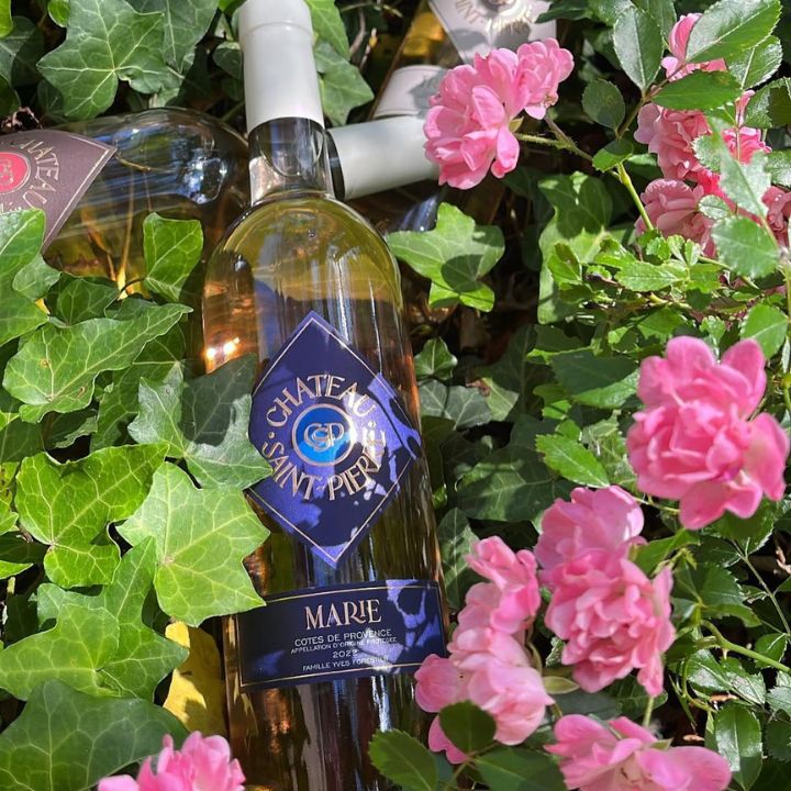 Bottle of Chateau Saint Pierre Provence Marie rose wine surrounded by pink flowers and green leaves