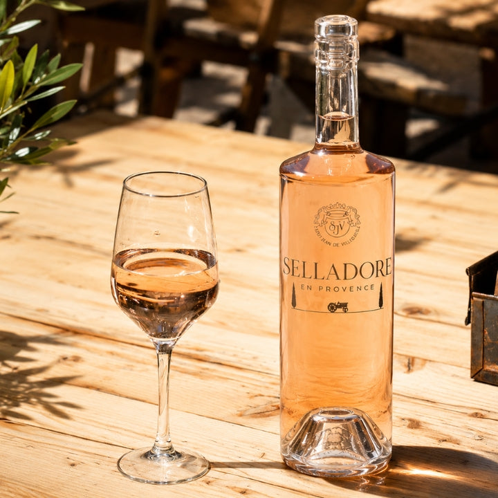 Bottle and glass of Selladore rose wine on a wooden table outdoors.