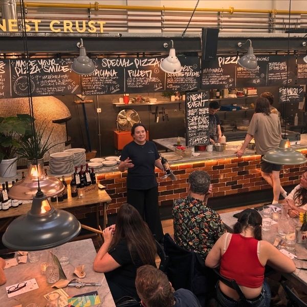 Reserve Wines' Amy talks to the dining audience about a red wine  for spring. She stands in front on the honest crust open kitchen in Picturedrome Macclesfied.