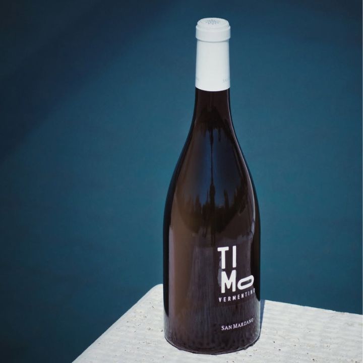 Bottle of Timo Vermouth on a textured surface with a blue gradient background