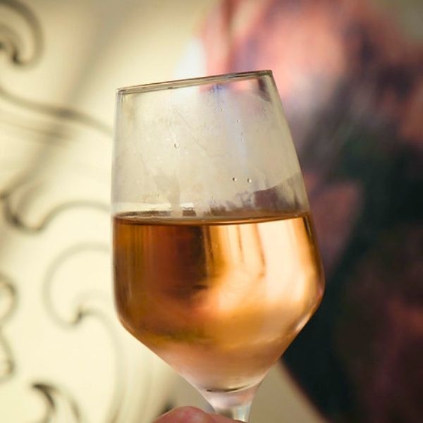 Glass of rose wine held by a person against a blurred background
