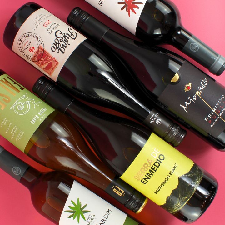 Collection of wine bottles with various labels on a pink background