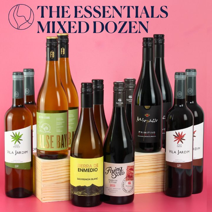 Collection of wine bottles with labels on a pink background, featuring 'The Essentials Mixed Dozen' text.